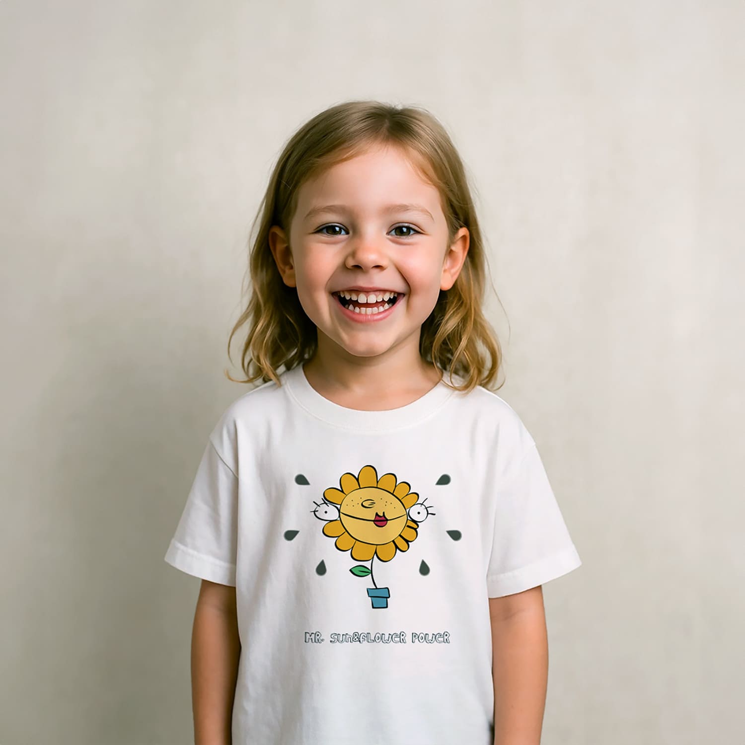 Niño rubio de unos 6 años vistiendo una camiseta de manga corta con el estampado de Little Yellow Caul&Flower, y jugando con dos donuts de colores como su fuesen gafas